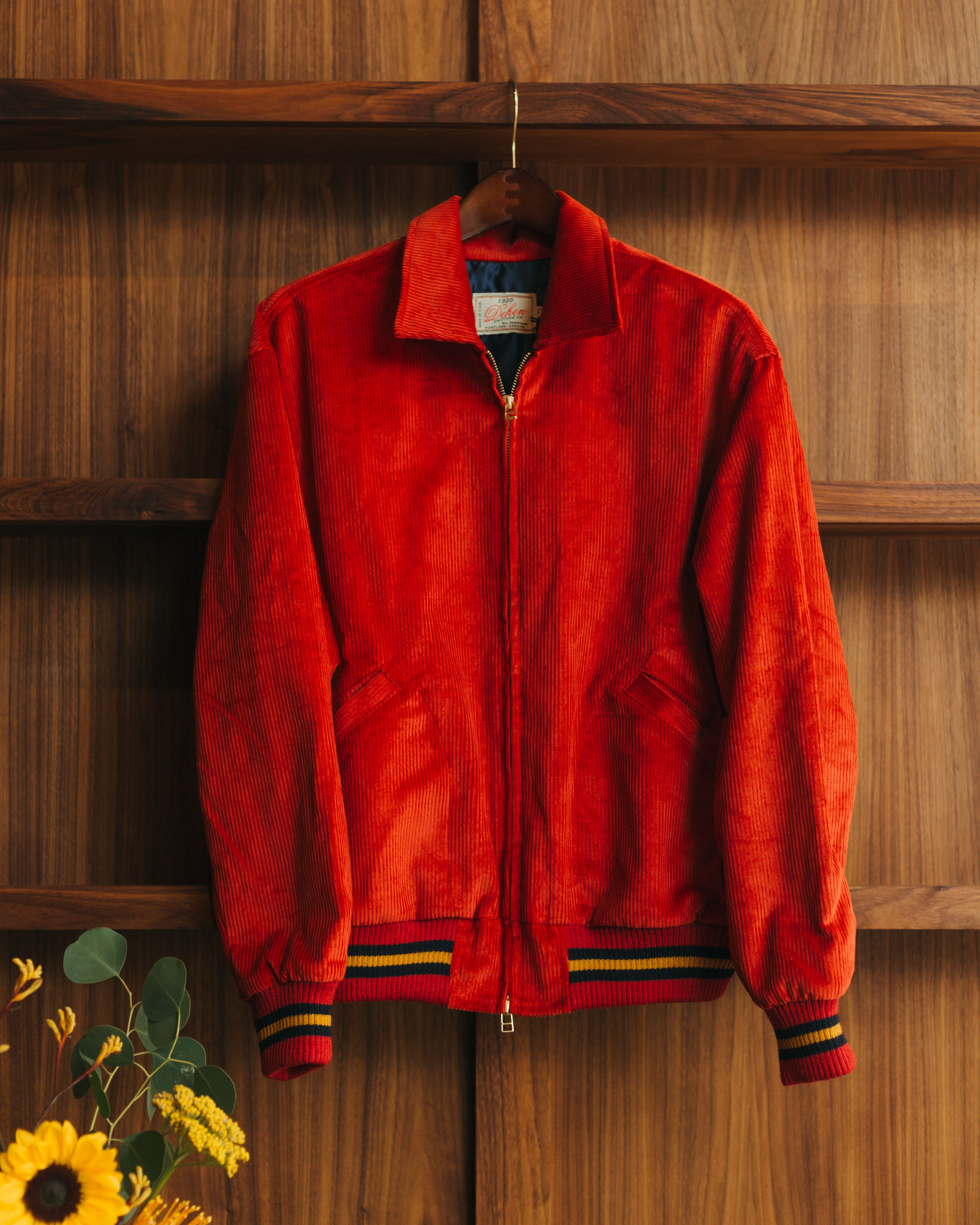 Red jacket hanging on a wooden shelf with flowers in the foreground from Dehen1920