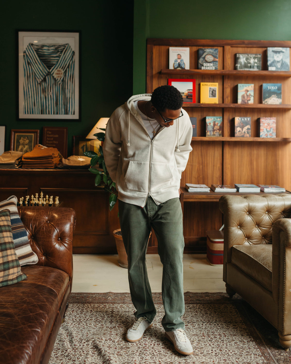 Man in Zip Hoodie against wooden bookcase at Fancy Groceries