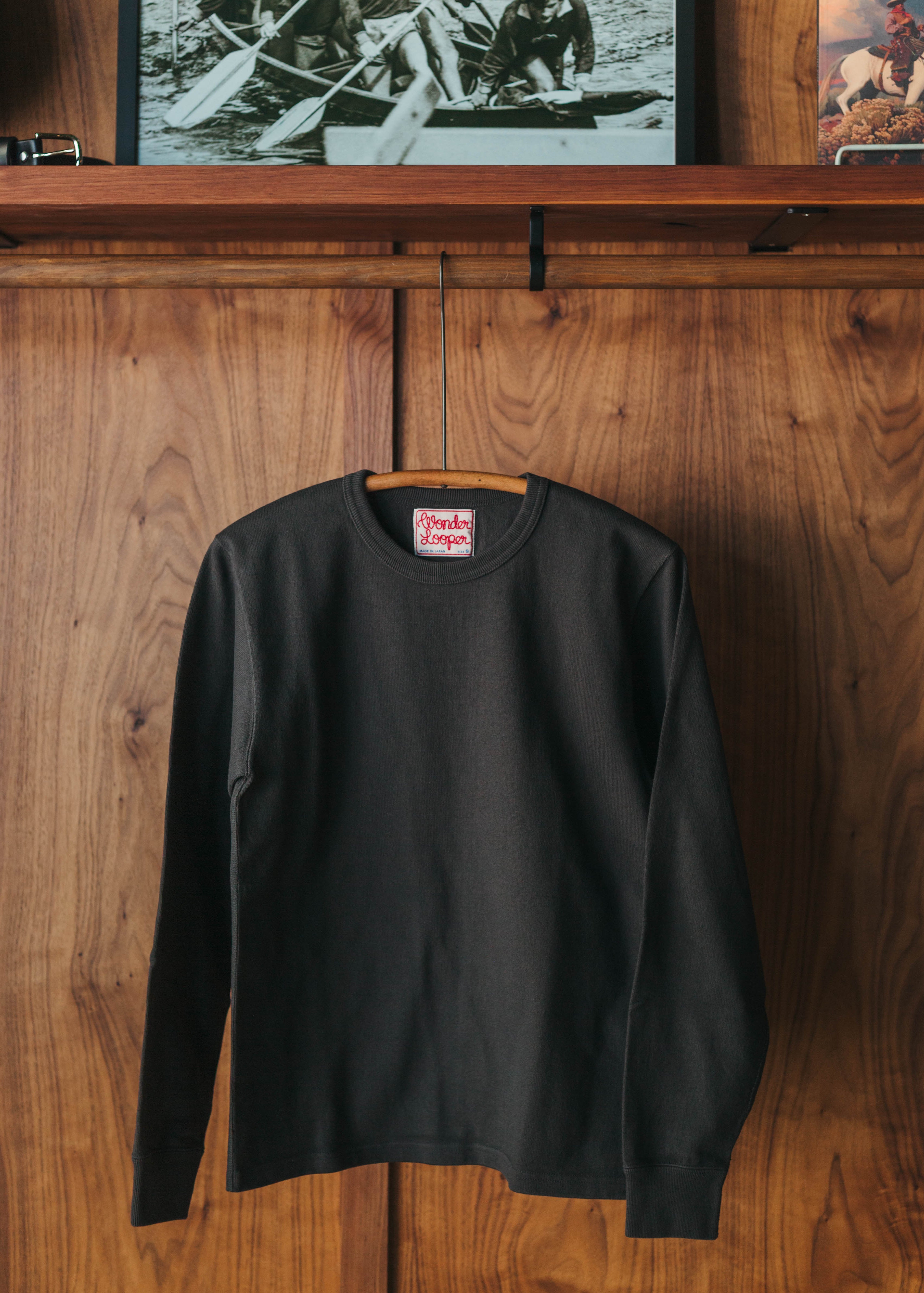 Black long-sleeve shirt with a brand label on a wooden surface at Fancy Groceries