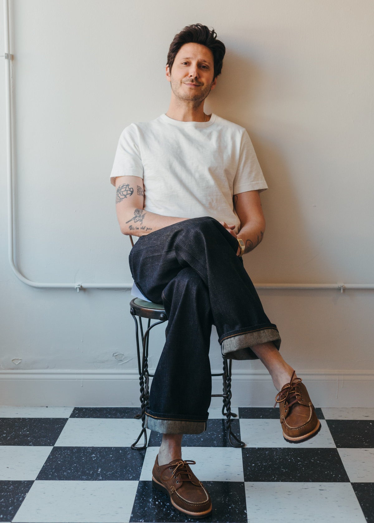 Man in a white tee wearing Harionago Strong Guy selvedge wide leg denim against a white wall and black and white tile