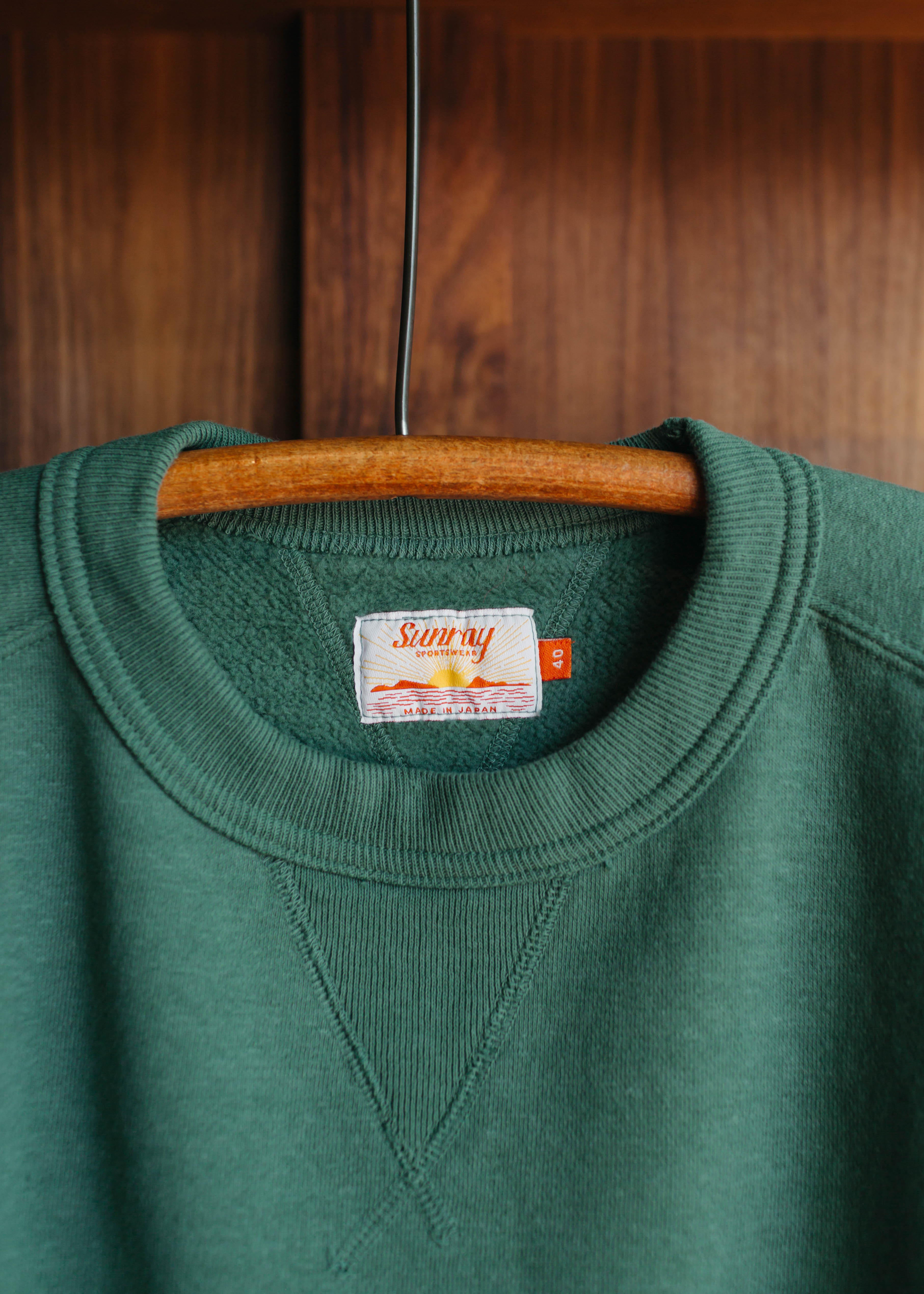 Green Sunray Sportswear sweatshirt  label on a wooden hanger against a wooden background