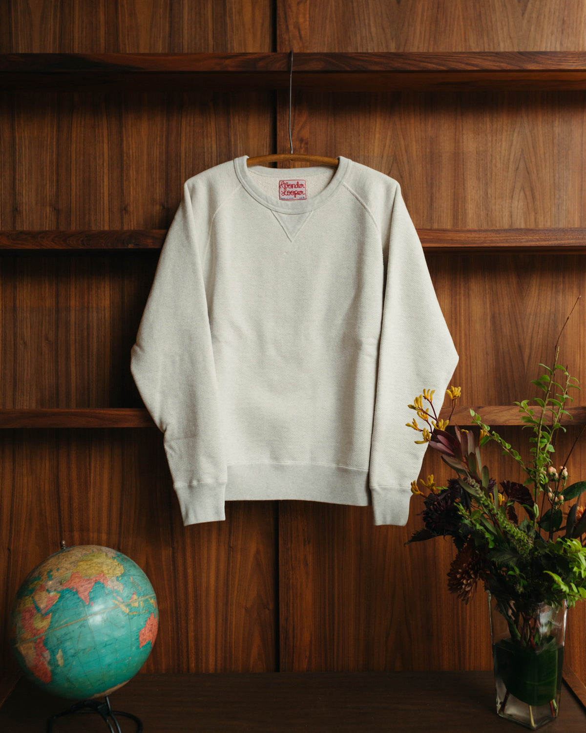 Wonder Looper Crewneck hanging against a wooden wall